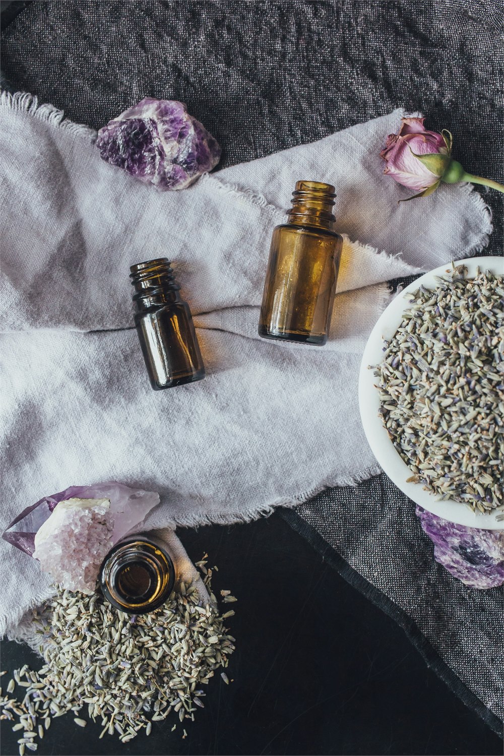 Amber essential oil bottles, lavender buds and amethyst crystals